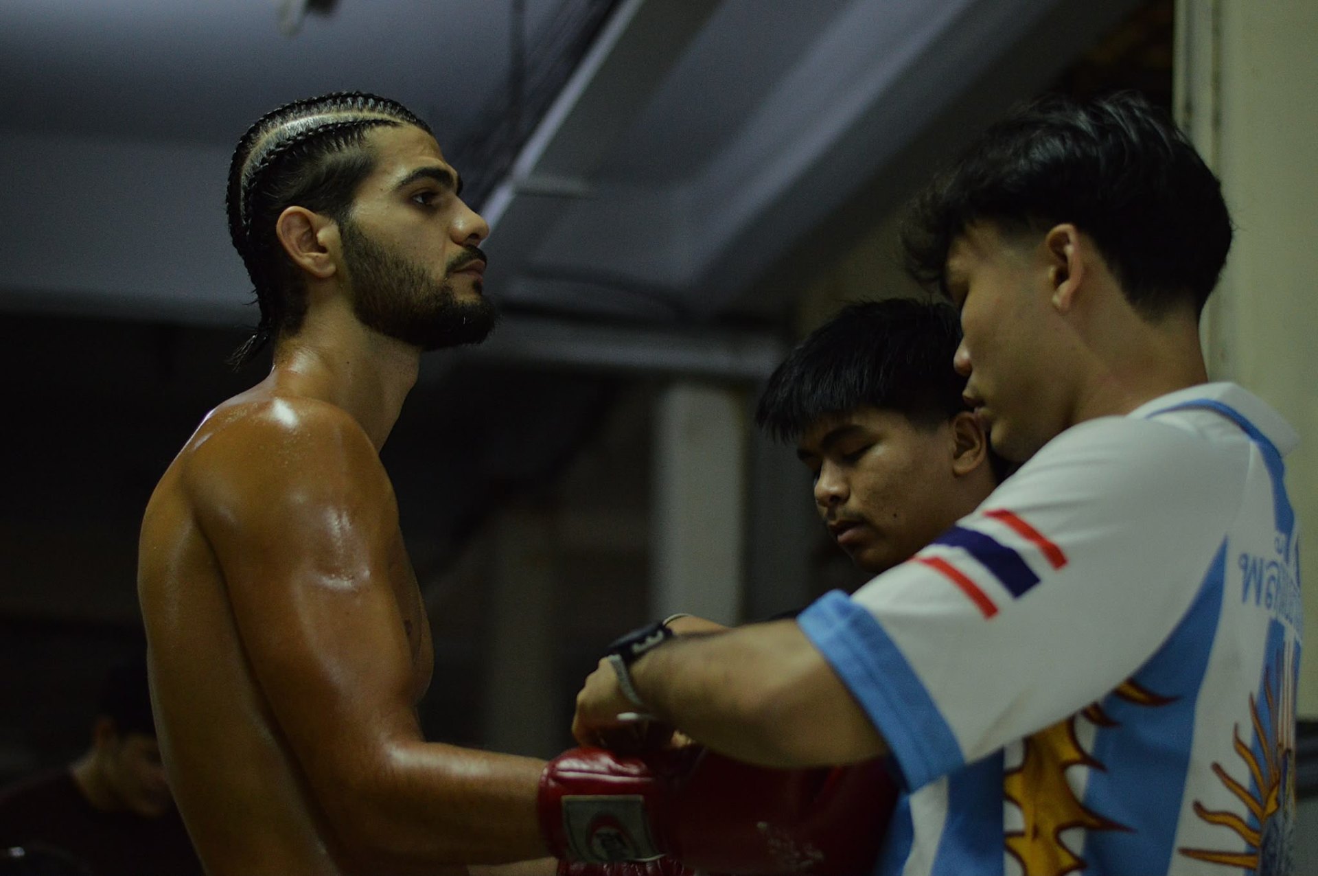 Coaches wrapping fighter's gloves before stepping into the ring