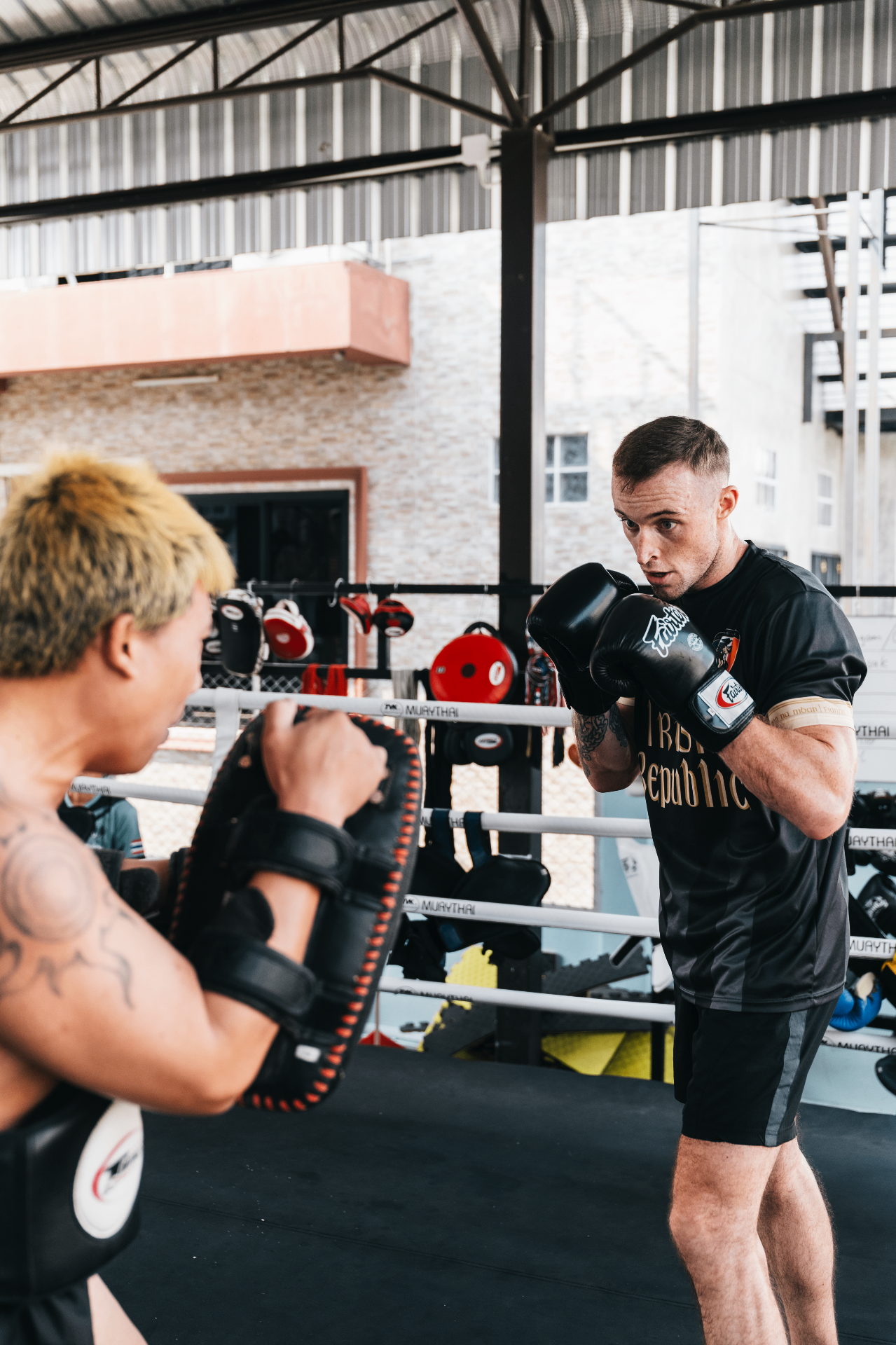 Fighter doing padwork with coach in the gym ring