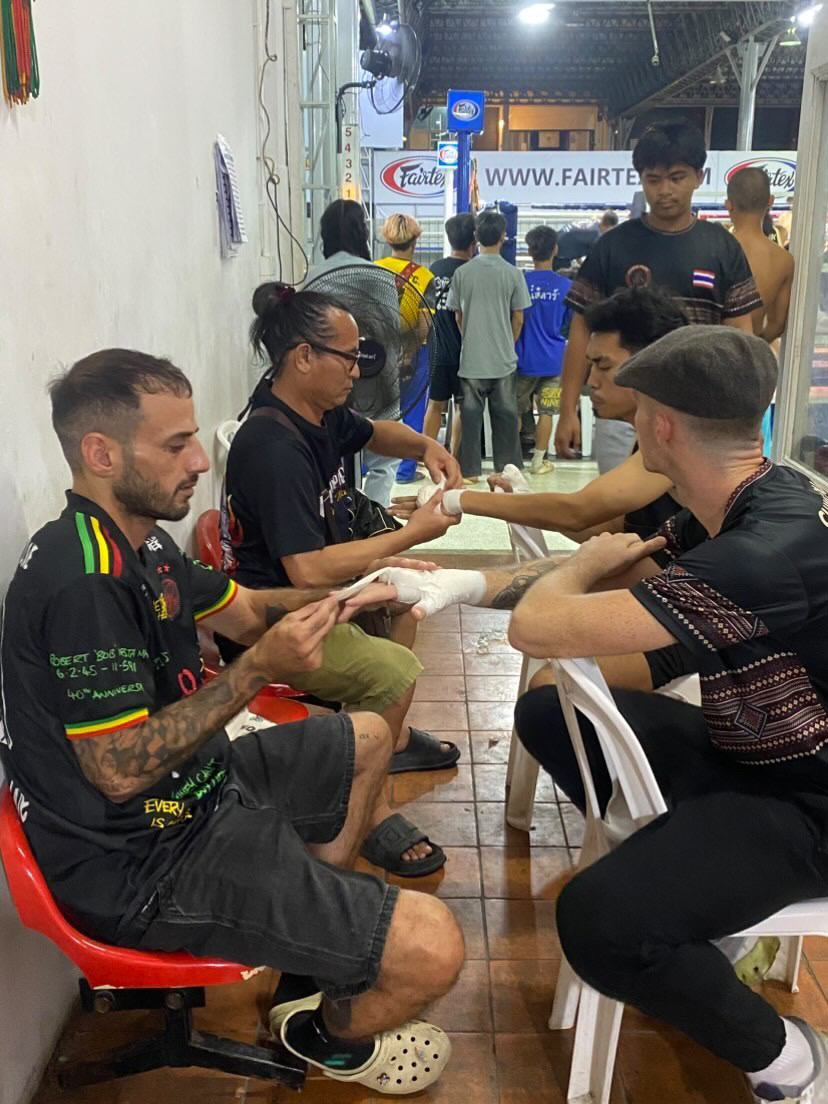 Coaches wrapping fighter's gloves before stepping into the ring