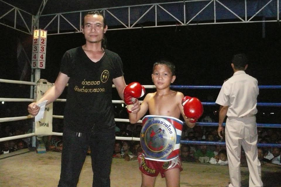 Kru Roen with a young fighter holding a championship belt after a win