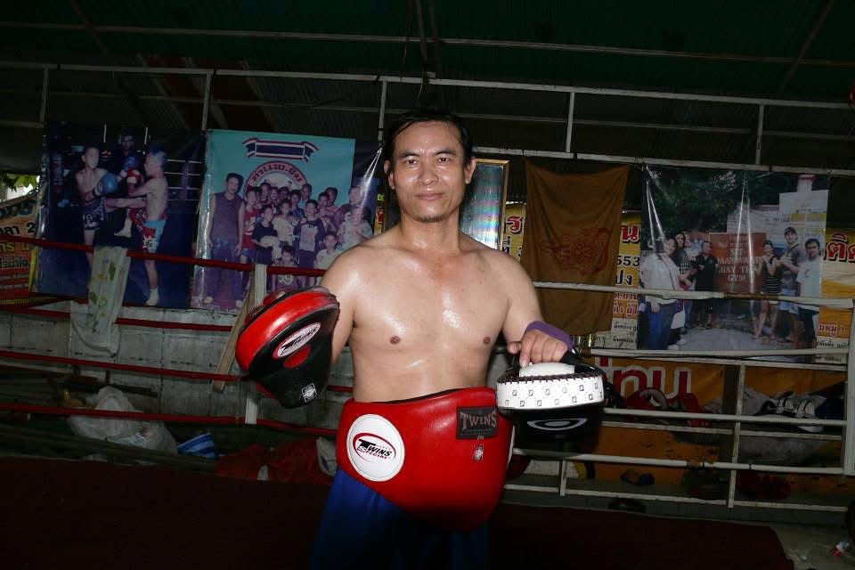 Kru Roen in a pad-work stance, shirtless and sweating in the old gym