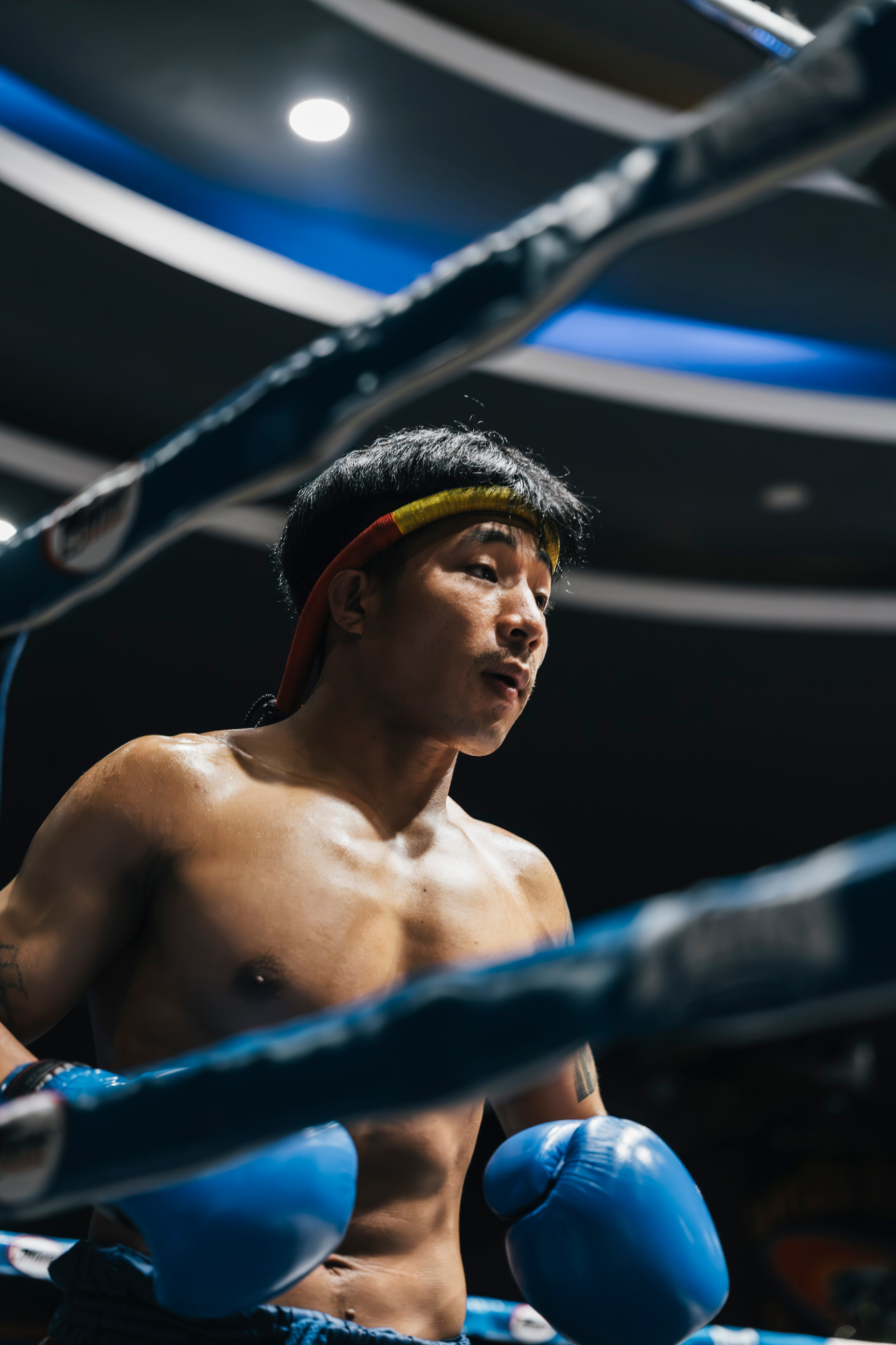 Fighter in the blue corner with mongkol under stadium lights