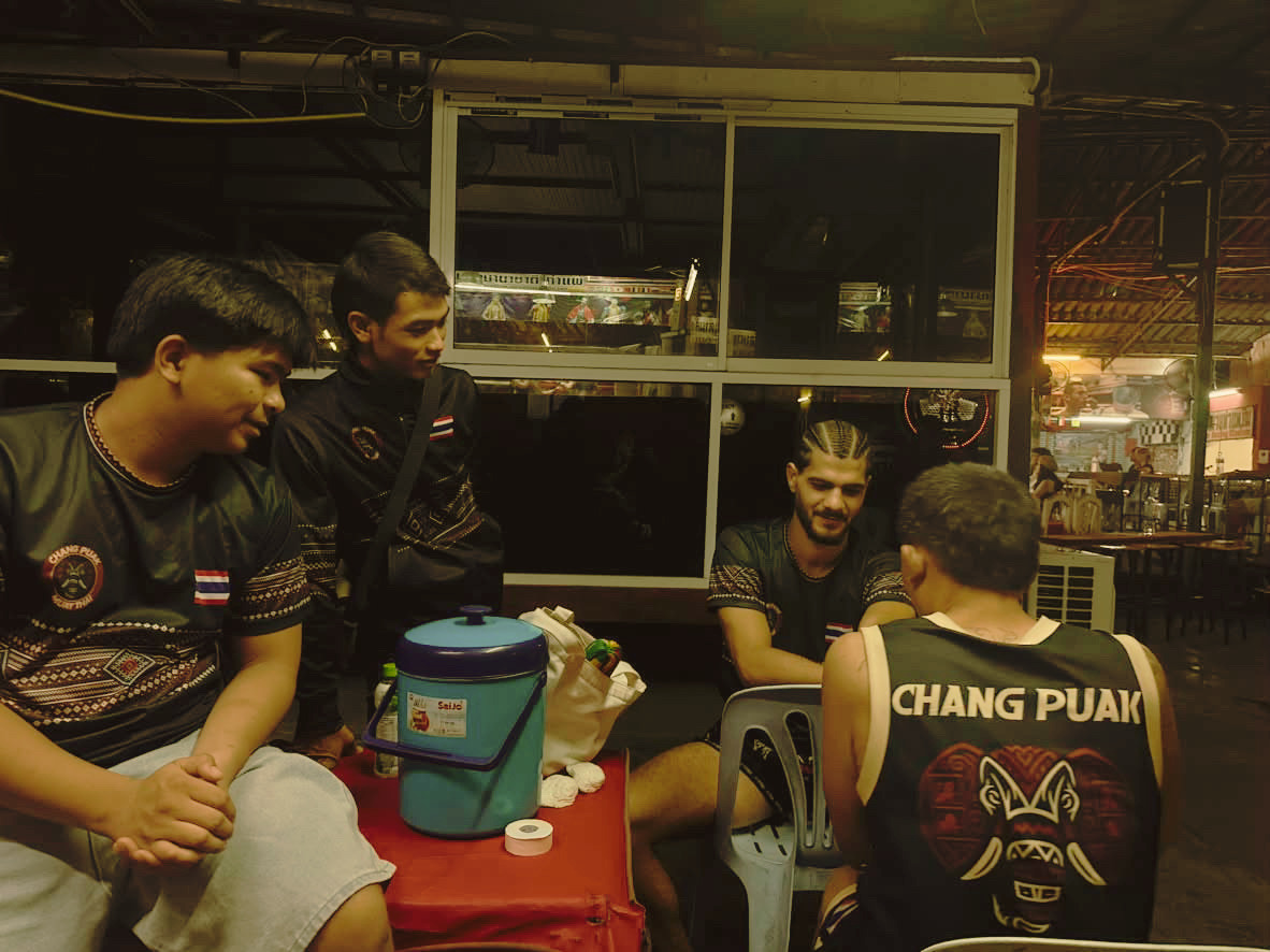 Changpuak team gathered around a table at night between fights